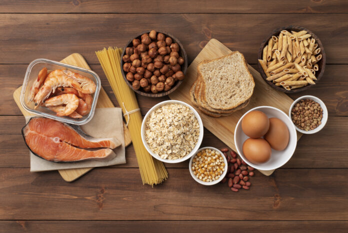 Variedade de alimentos ricos em carboidratos complexos sobre uma mesa de madeira.