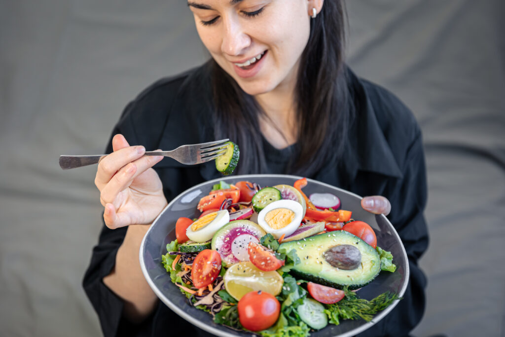 Mulher comendo salada com abacate e ovo, exemplo de refeição da dieta cetogênica