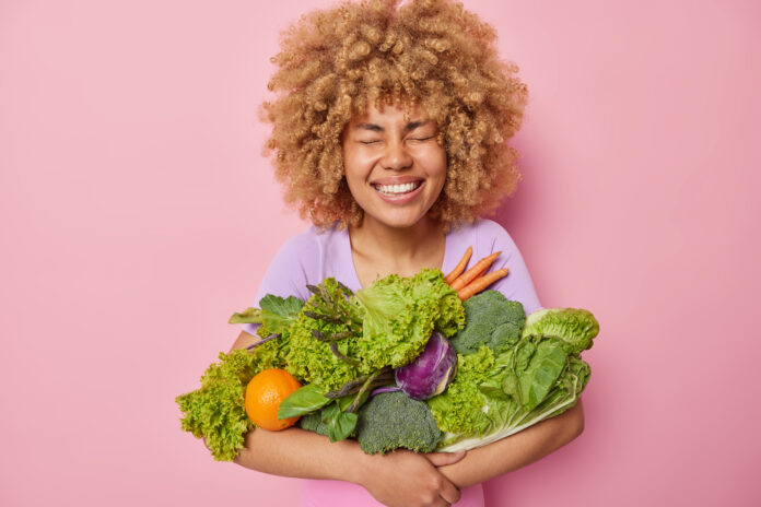 Mulher segurando uma variedade de vegetais frescos, representando a dieta vegetariana para emagrecimento.