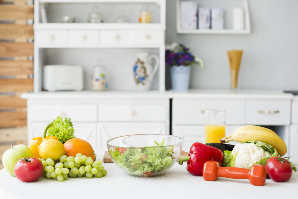 Ingredientes frescos para dieta vegana em mesa com haltere e suco.