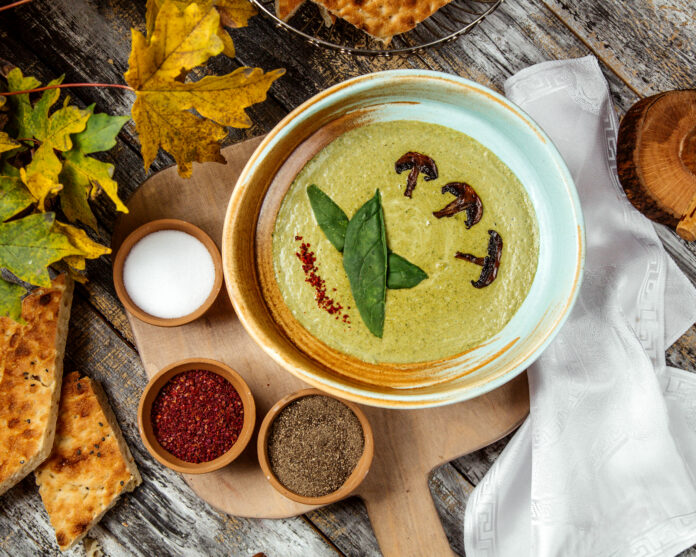 Sopa detox de espinafre com cogumelos e temperos em uma mesa rústica