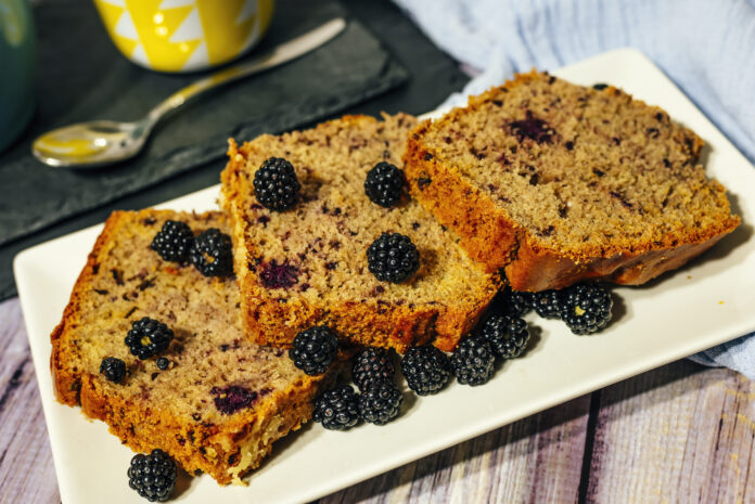 Fatias de bolo saudável com amoras frescas em um prato branco, destacando uma opção nutritiva e com baixo teor de açúcar.