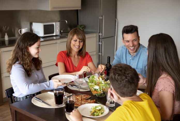 Família sorridente reunida em uma refeição à mesa, desfrutando de um momento harmonioso.