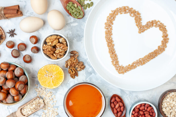 Prato decorado com grãos formando um coração, cercado por nozes, sementes, frutas cítricas e outros alimentos ricos em nutrientes.