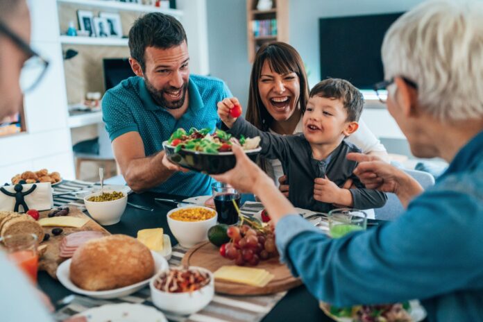 Família reunida à mesa compartilhando uma refeição saudável com pratos variados e momentos de alegria.