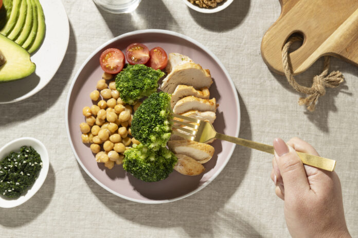 Prato equilibrado com frango grelhado, brócolis, grão-de-bico, tomate cereja e abacate, representando a dieta flexitariana.