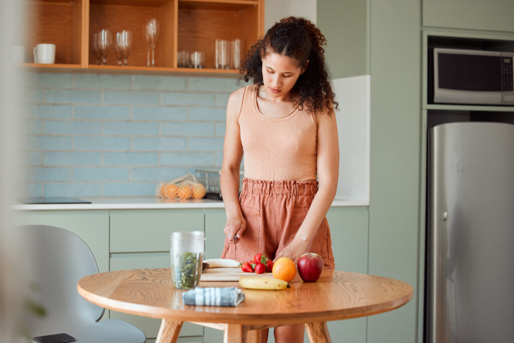 Mulher preparando lanches saudáveis com frutas frescas em uma cozinha moderna.