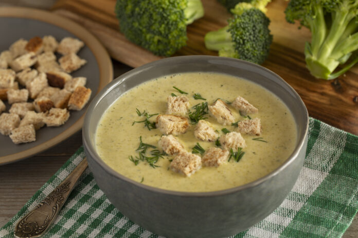 Tigela de sopa low carb com brócolis, croutons e ervas frescas.